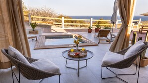 Una terrazza con sedie in vimini, un tavolino con vassoio per bevande e vista sul mare.
