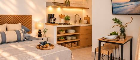 Un dormitorio con cama, mesita de noche y velador. Hay una pequeña mesa con una silla y un televisor montado en la pared.