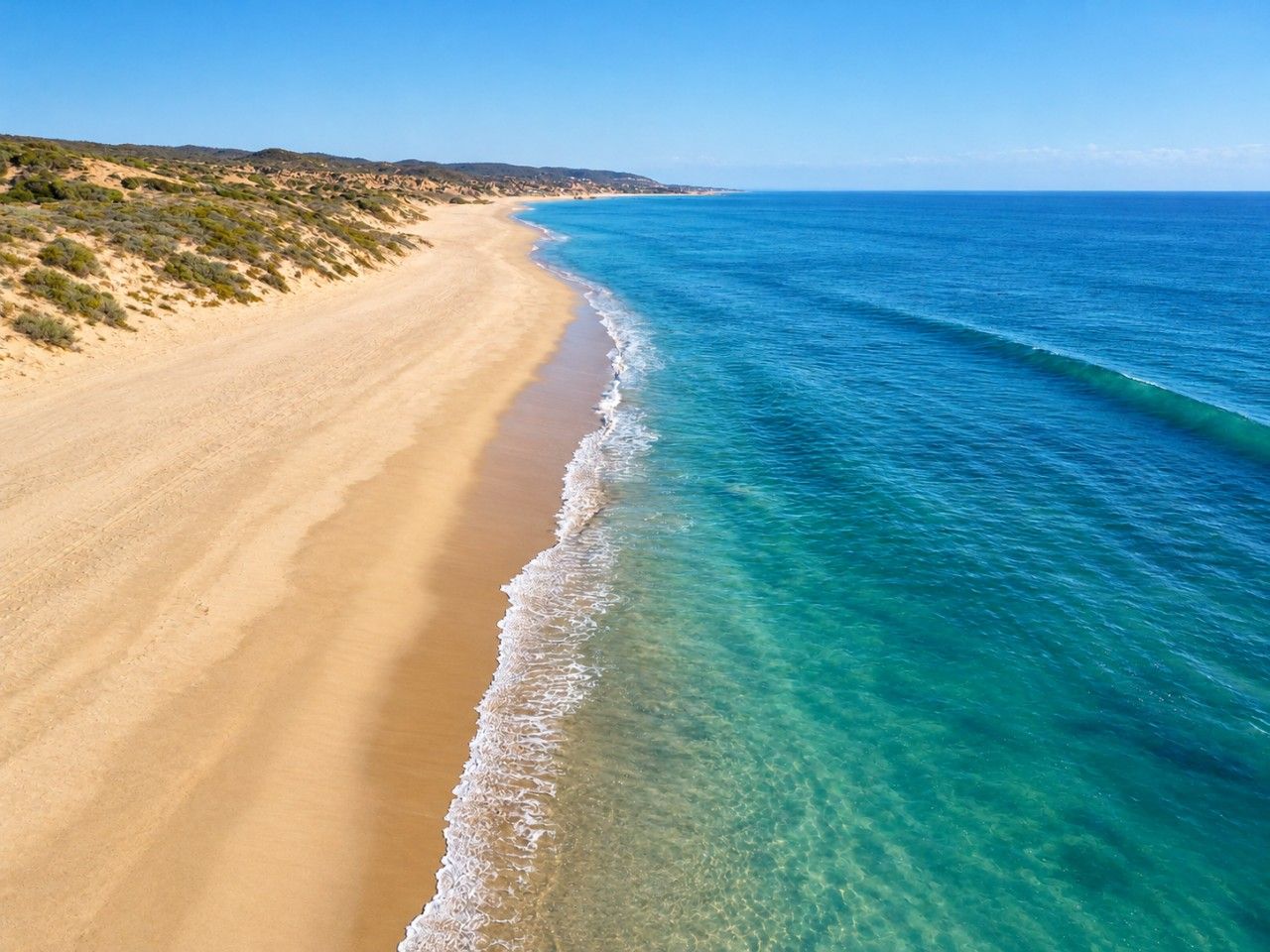 Una platja amb aigua cristal·lina i sorra daurada.