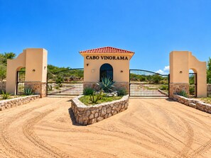 A gated entrance with a sign reading 'CABO VINORAMA' and a landscaped area with plants.