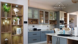 Une cuisine moderne avec des meubles gris, un îlot central doté d’un évier et divers appareils de cuisine.
