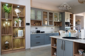 Una cocina moderna con armarios grises, una isla central con fregadero y diversos electrodomésticos.