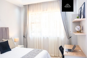 Una habitación de hotel moderna con una cama grande, un escritorio con una computadora portátil y un globo en un estante.