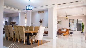 Un intérieur moderne comprenant un coin repas avec une table et des chaises en bois, un salon avec un canapé et une table basse, et une cuisine en arrière-plan.