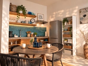 Une cuisine moderne avec une table ronde en bois, des chaises et un réfrigérateur encastré.