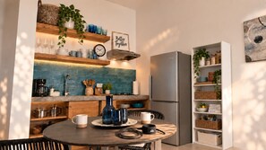 A modern kitchen with a central island, built-in shelves, and a refrigerator.
