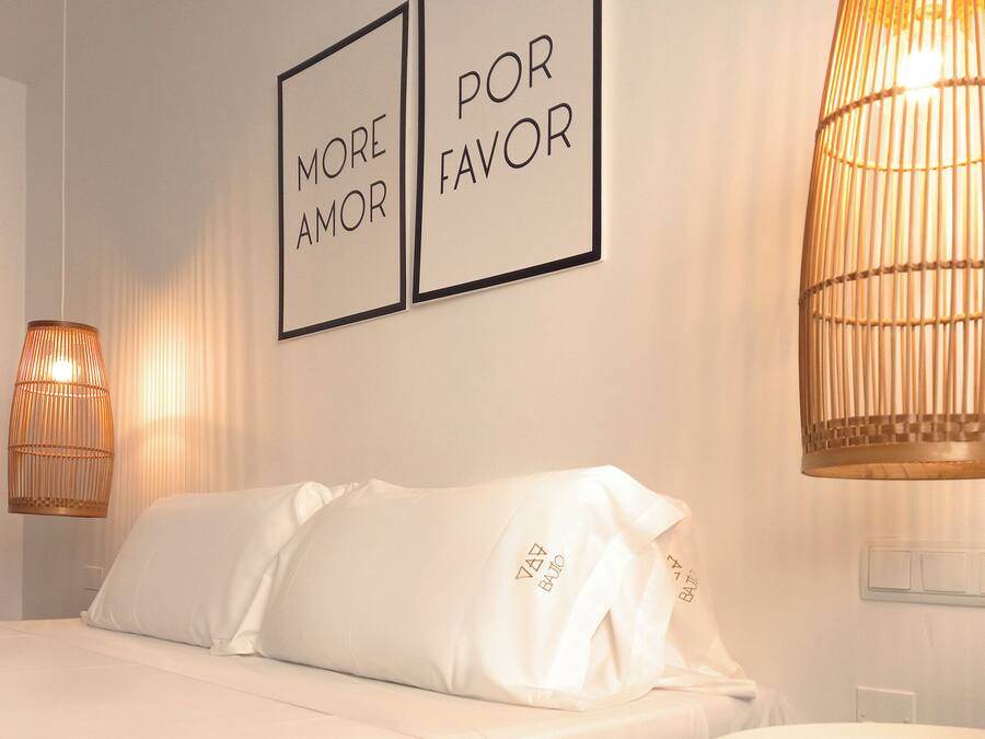 Une chambre d’hôtel comprenant un lit, deux lampes fixées au mur et une prise électrique fixée au mur.