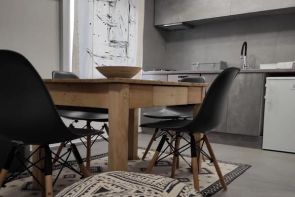 A modern kitchen with a wooden table, black chairs, and a white refrigerator.