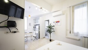 A hotel room with a bed, a TV mounted on the wall, a desk, and a chair. - Sarpi Flat (Firenze)