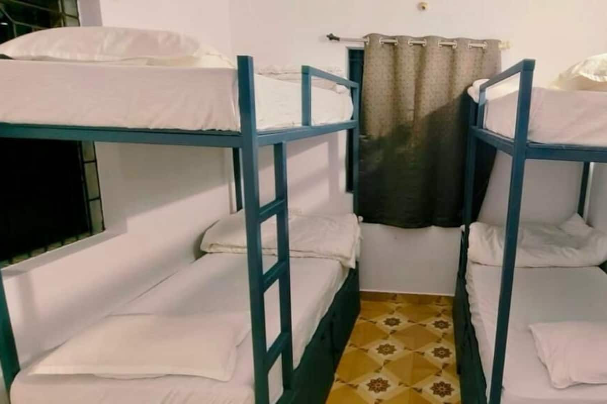 A dormitory room with bunk beds, a patterned floor, and a curtain.