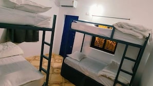 A dormitory room with bunk beds, a blue door, and a small window with curtains. - Karma Stays Hostel Morjim (Morjim)