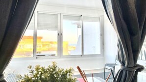 Un balcón con vistas a edificios y una planta al frente.