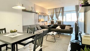 Una sala de estar moderna con un conjunto de sofás, una mesa de comedor y una mesa de centro.