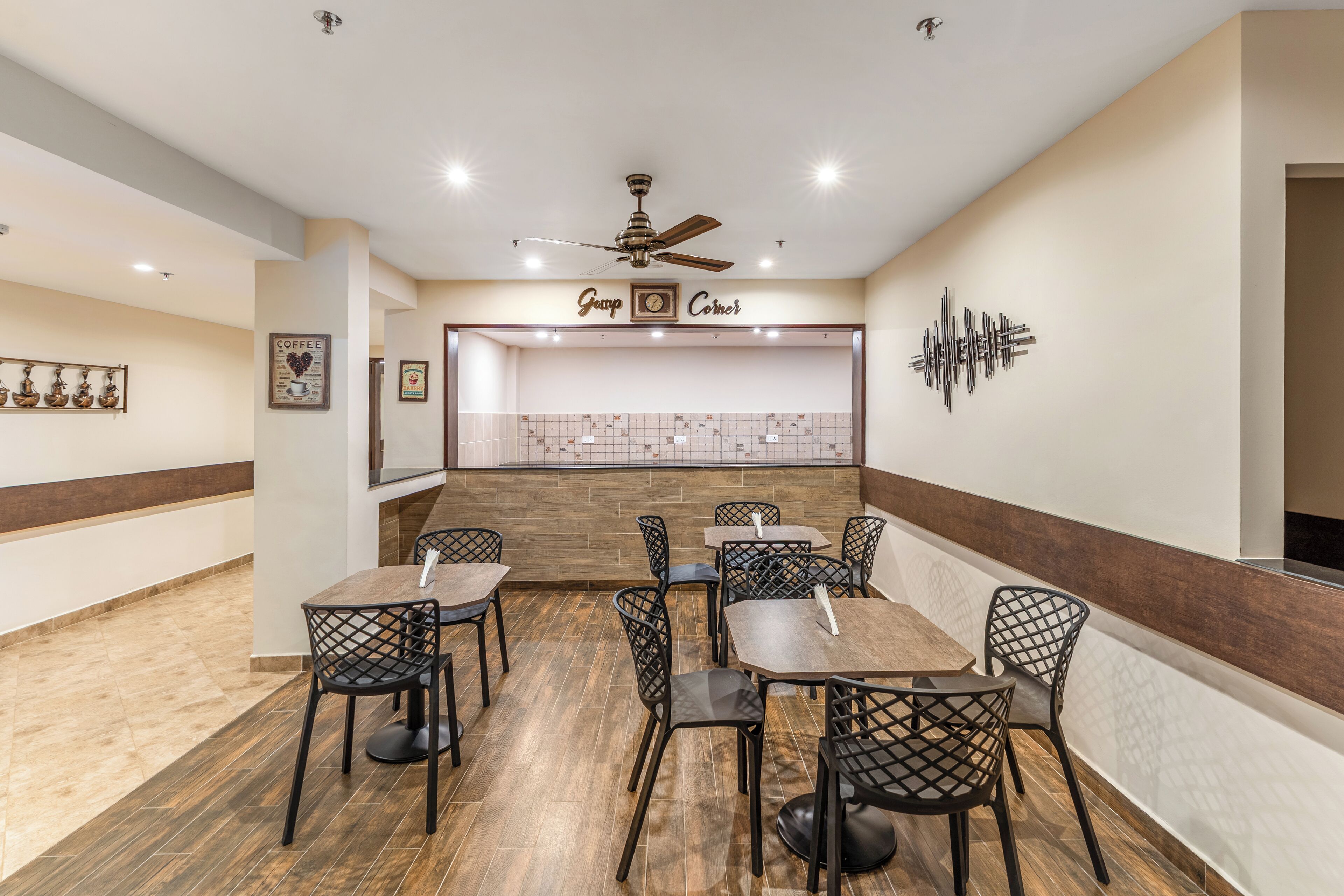 A restaurant with a wooden floor, black chairs, and a ceiling fan.
