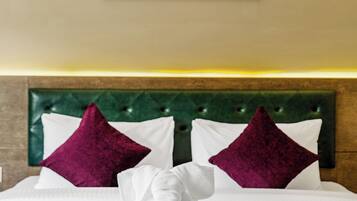 Habitación de hotel con cama, dos almohadas, cabecero y un cuadro en la pared.