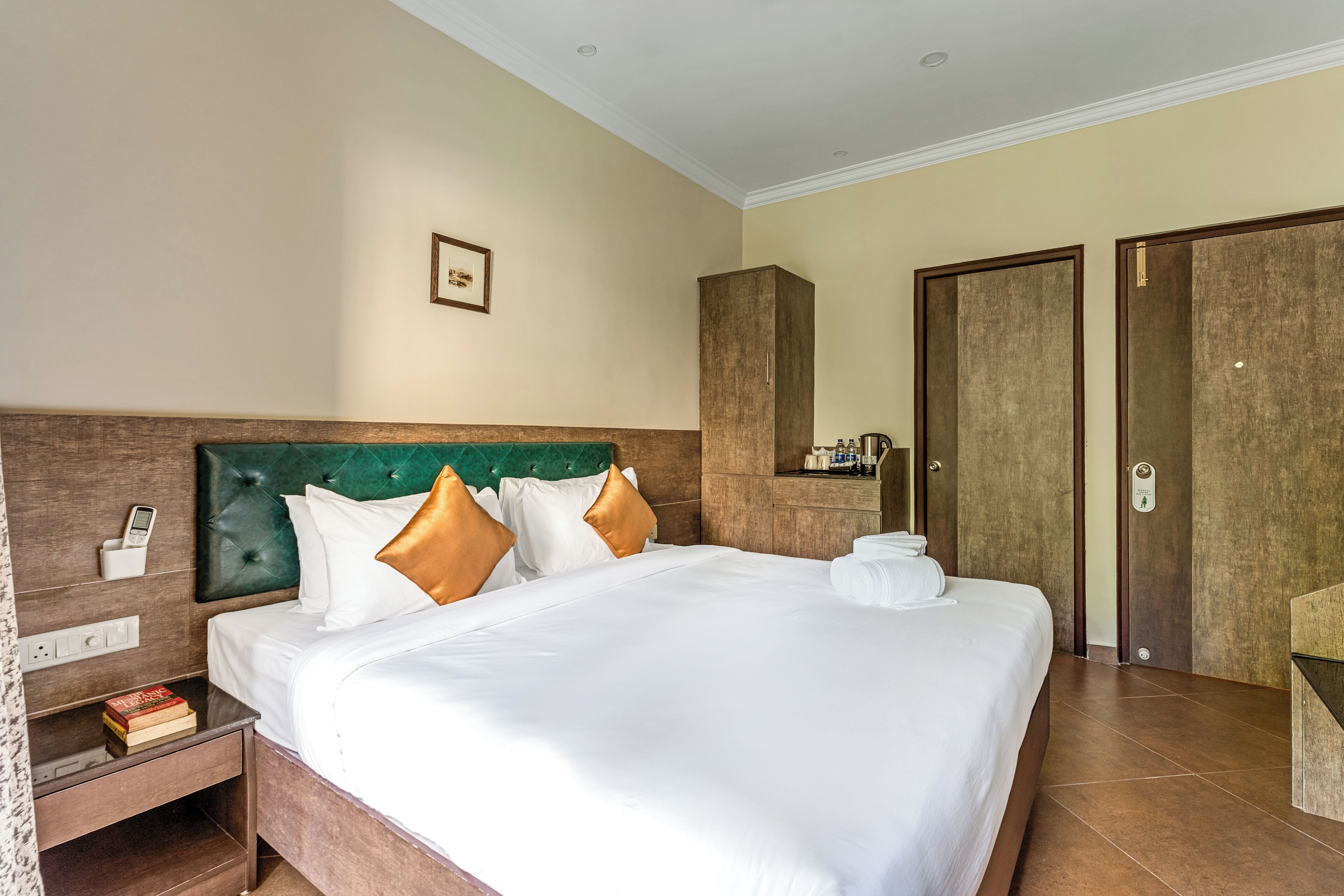 Una habitación de hotel con una cama grande, una mesita de noche con un teléfono y un armario.