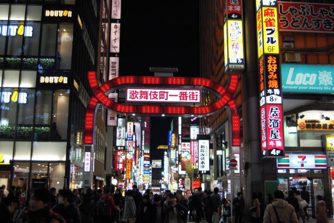 A busy urban street at night with illuminated signs and storefronts.