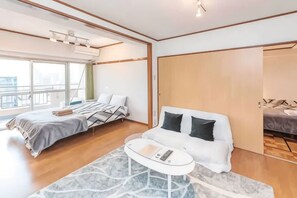 Una habitación de hotel moderna con una cama, un sofá, una mesita de café y un ventanal grande.