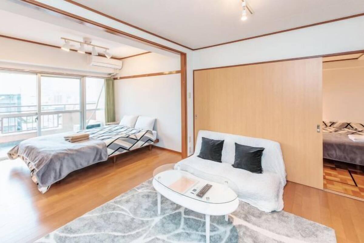 Un dormitorio moderno con cama, sofá, una mesita de centro y un ventanal grande.