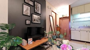 A living room with a flat-screen TV, framed pictures, a wooden coffee table, and a potted plant. - Yotsuya Matsumoto Hotel (Tokyo)