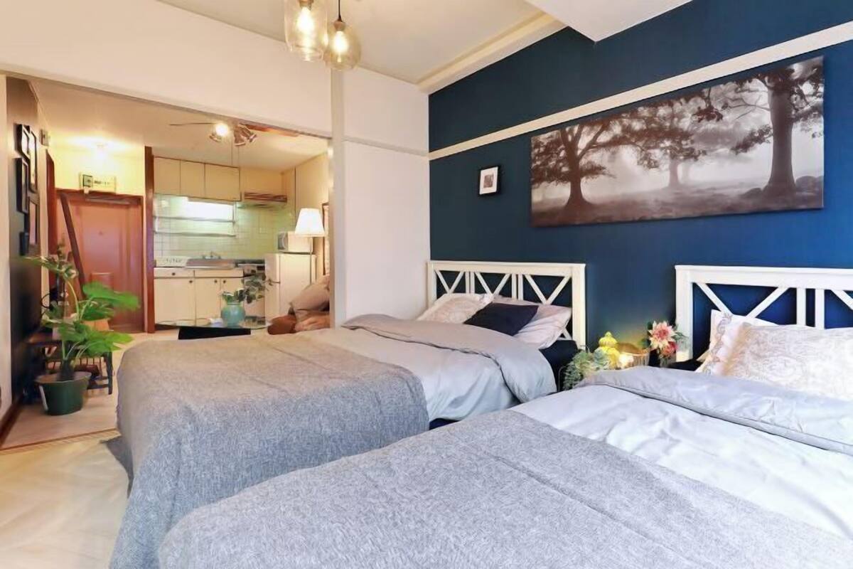 Un dormitorio con dos camas, un cuadro de árboles y vistas a la cocina.