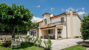 A two-story house with a stone facade, a balcony, and a garden with a swing chair. - Countryside Villa Tajo - Four Bedroom Holiday Home  with Swimming Pool (Imotski)