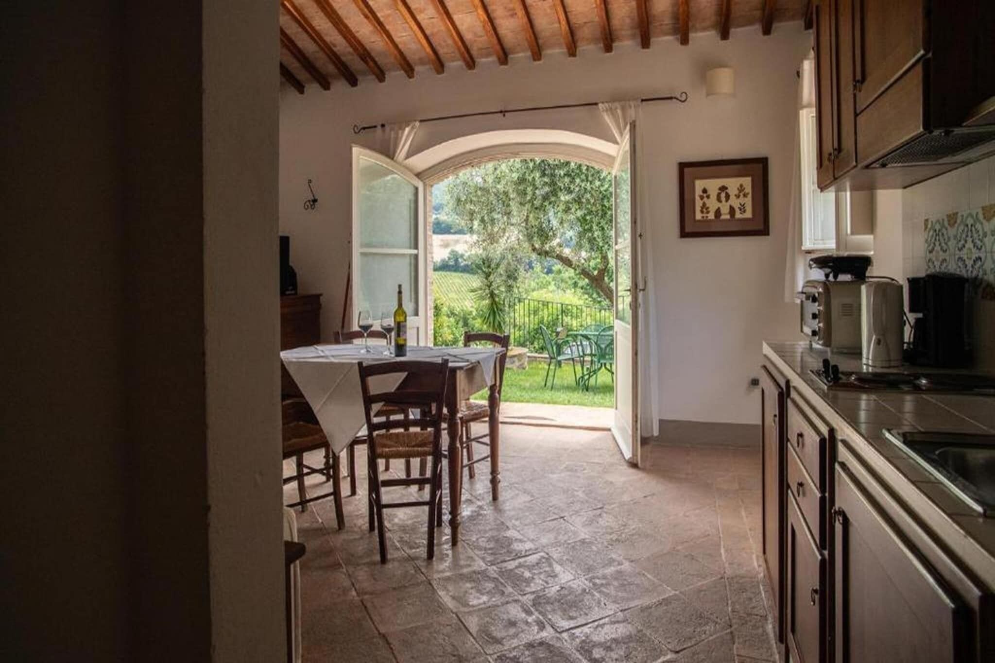 A kitchen with a stone floor, wooden cabinets, and a view of a garden through an open doorway.