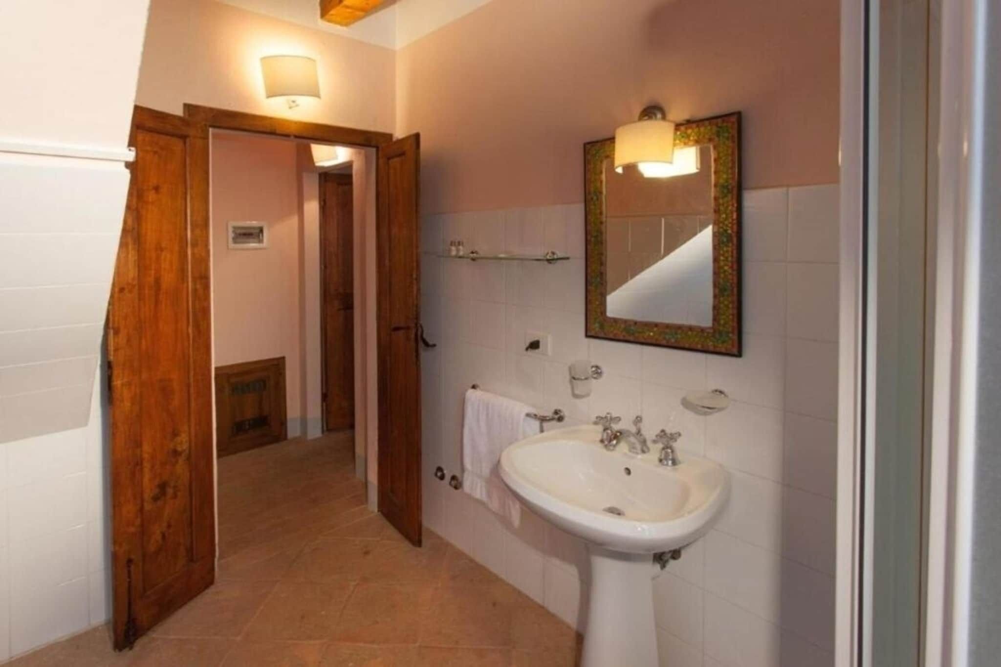 A bathroom with a white sink, a mirror with a decorative frame, and a wooden door leading to another room.