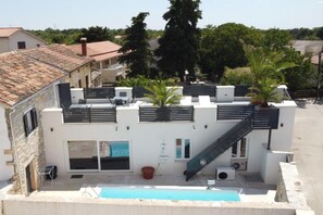 A modern building with a rooftop pool, a staircase, and a small garden area with a palm tree. - Villa Galant with Pool & Sauna Maružini (Kanfanar)