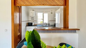 A modern kitchen with white cabinets, a built-in microwave, and a water heater.