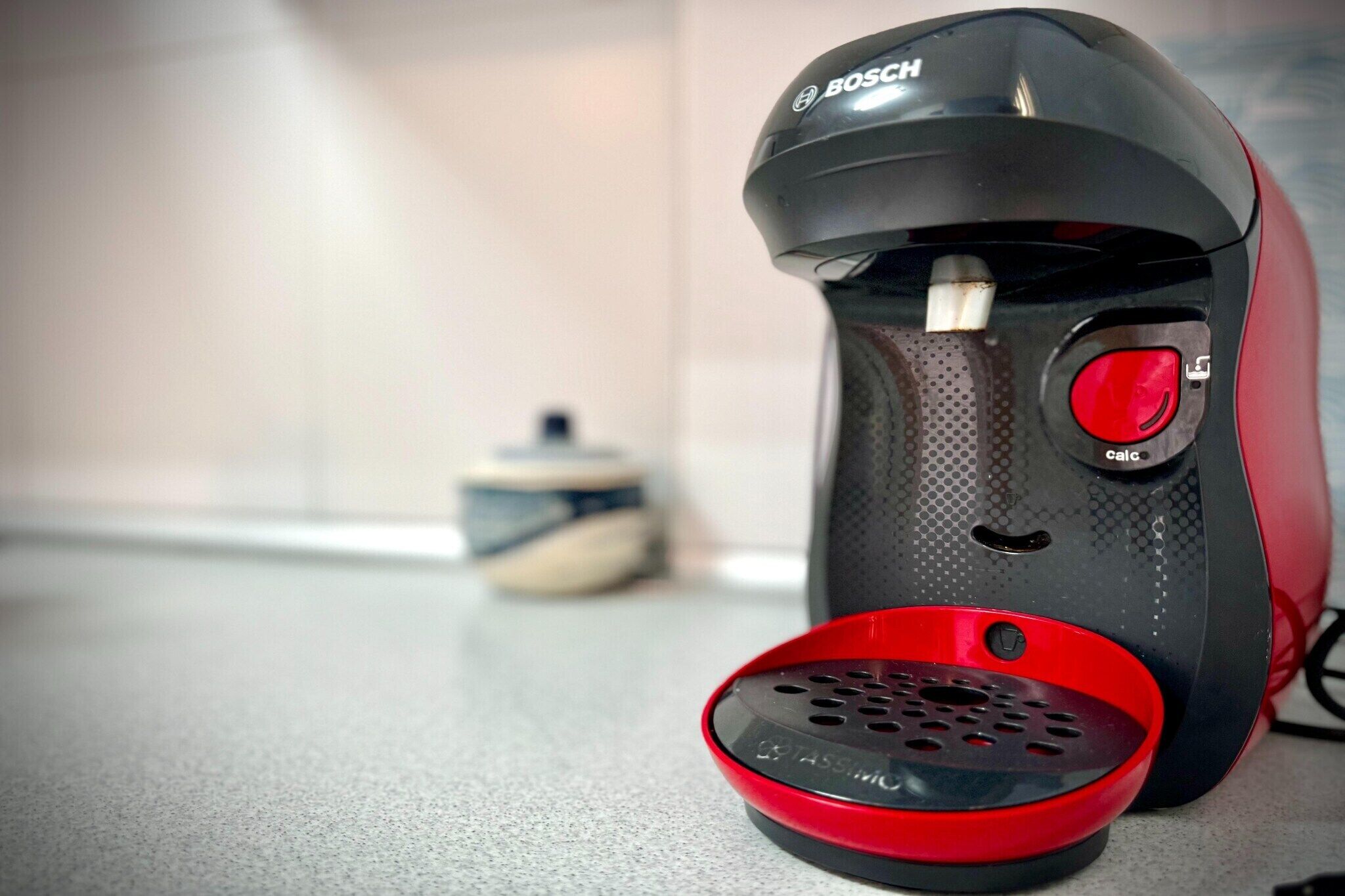 A Bosch coffee maker with a red drip tray on a kitchen counter.