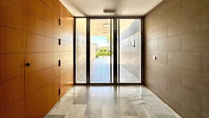 A corridor with a wooden wall on one side and a tiled wall on the other, leading to an open area with a view of greenery. - Apartment in Poblado Golf near Playa Serena (Roquetas de Mar)