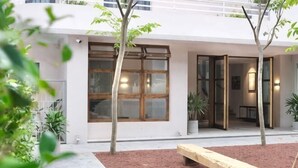 A building with large windows, a bench, and potted plants. - Express by M Village Tu Xuong, a brand of Modern Village Lifestyle (Ho Chi Minh City)