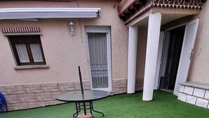 Ein Garten mit künstlichem Rasen, einem runden Tisch und einem Stuhl.