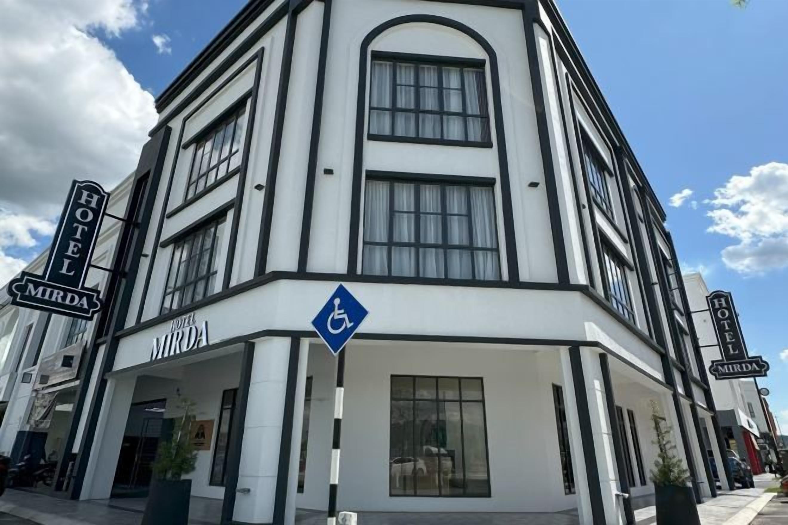 Ein Eckgebäude mit einem Schild für 'Hotel Mirada' und einem blauen Rollstuhlgerechter-Zugang-Schild.