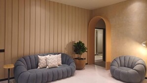 Una sala de estar moderna con un sofá, una silla, una planta en maceta y un ventilador de techo.