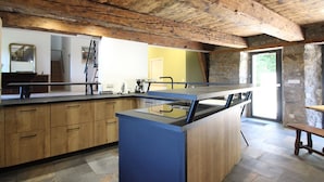 Une cuisine avec des meubles en bois, un îlot central bleu et un mur en pierre.
