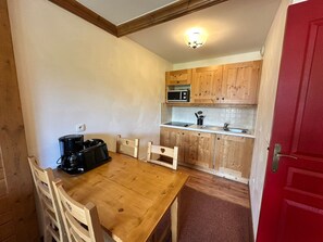 A compact kitchen with wooden cabinets, a microwave, and a coffee maker on a wooden table.