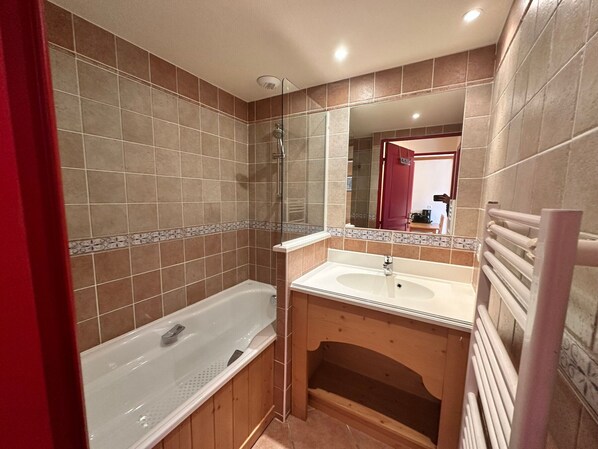A bathroom with a bathtub, sink, and mirror.