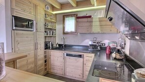 A compact kitchen with wooden cabinets, a built-in oven, a coffee machine, and a sink.