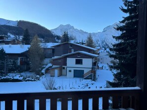 Ein Wohngebiet mit schneebedeckten Häusern und Bergen im Hintergrund.