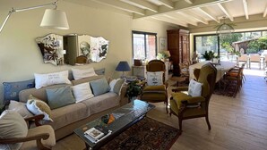 Ein gemütliches Wohnzimmer mit einer Couch, Sesseln, einem Couchtisch und einem Essbereich mit Stühlen und Tisch.