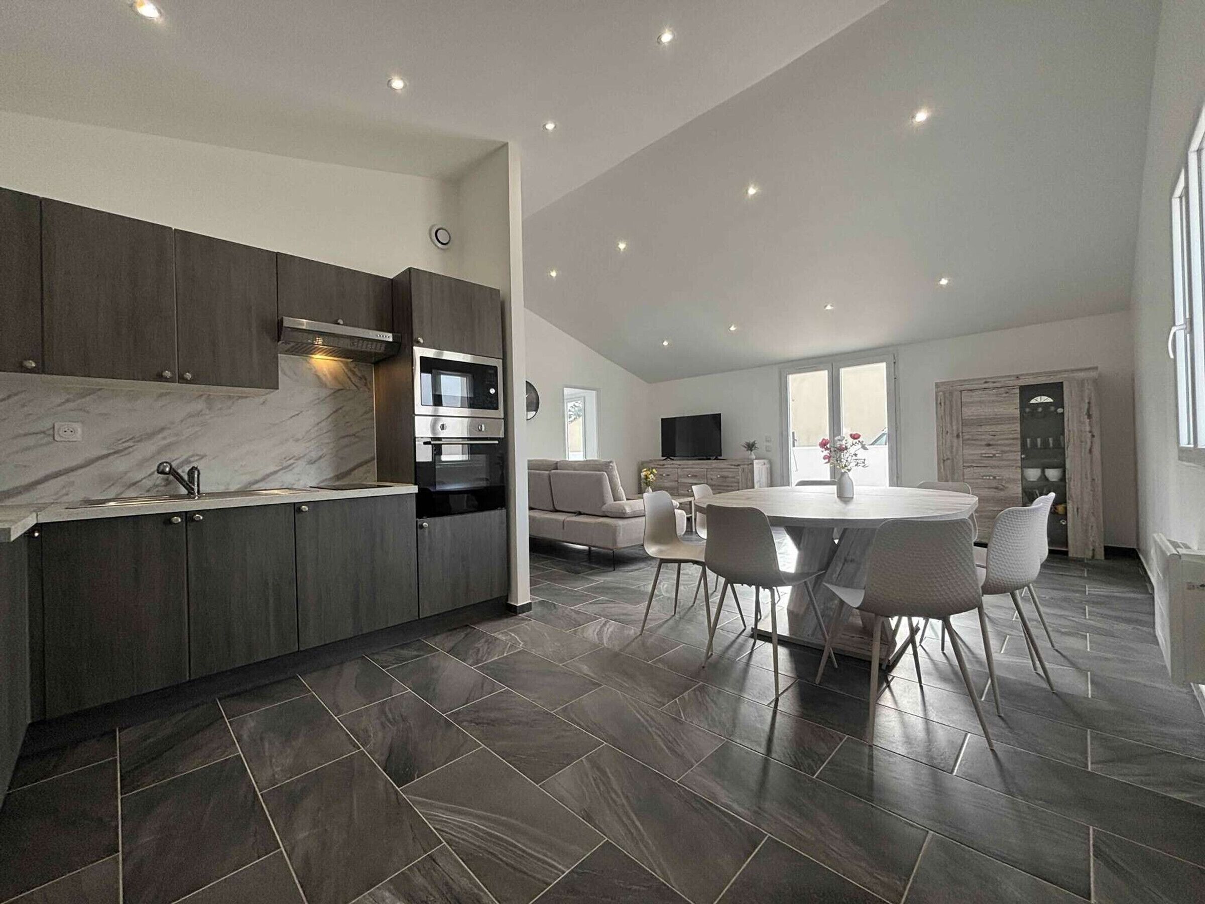 Et moderne køkken med mørke skabe, en indbygget ovn og en marmor bordplade.