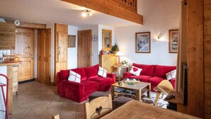 Un salon chaleureux avec des canapés rouges, un plafond en bois et un coin repas.