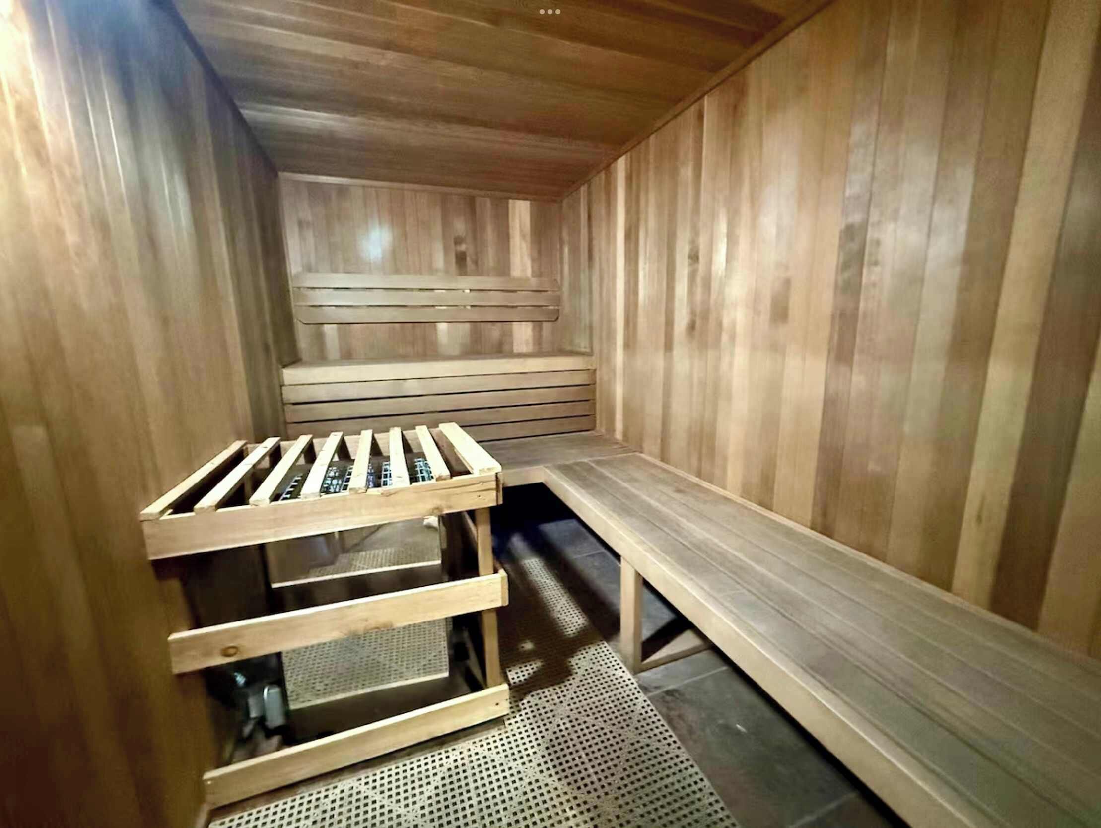 A sauna with wooden benches and a bench with a mesh backrest.