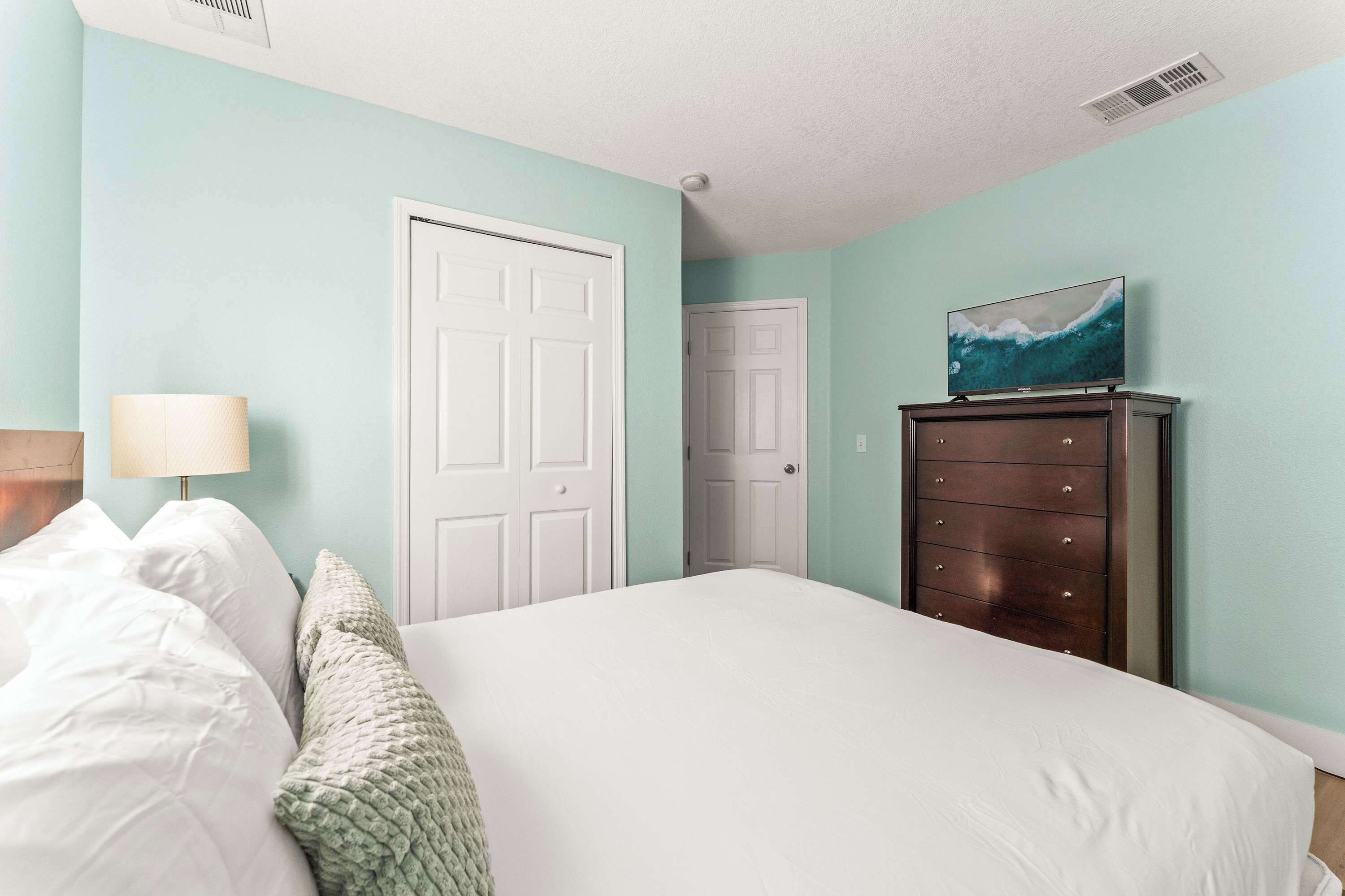 Un dormitorio con cama, cómoda, lámpara y puerta.