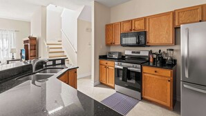 Una cocina moderna con una isla central, armarios de madera y electrodomésticos de acero inoxidable, incluyendo un microondas integrado.