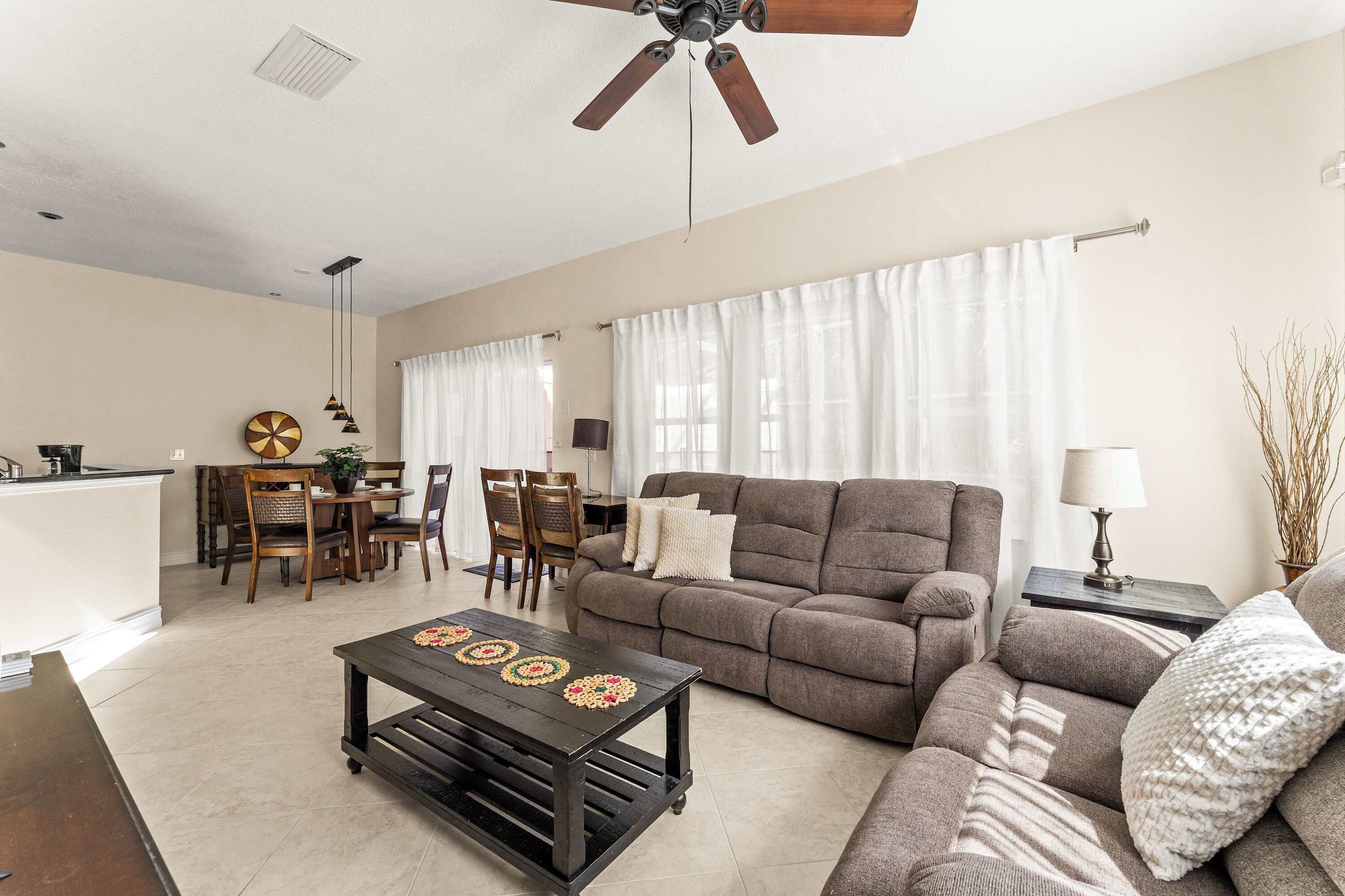 A living room with a sofa, a coffee table, a dining area with chairs and a table, and a kitchen area.