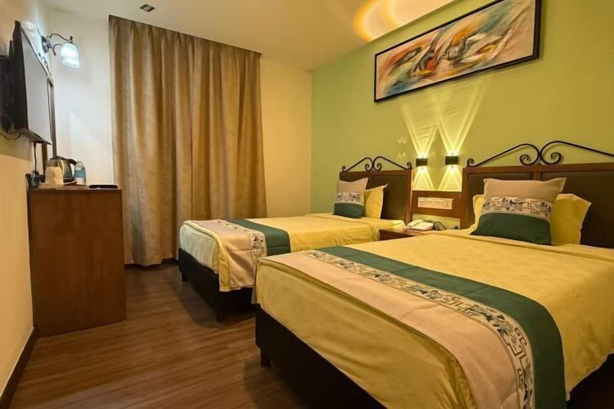 A hotel room with two beds, a desk with a lamp, a painting on the wall, and a curtain.