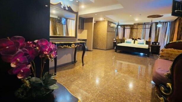 A hotel room with a bed, a mirror, a vanity, and a potted orchid. - K Garden Hotel Sungai Petani (Sungai Petani)